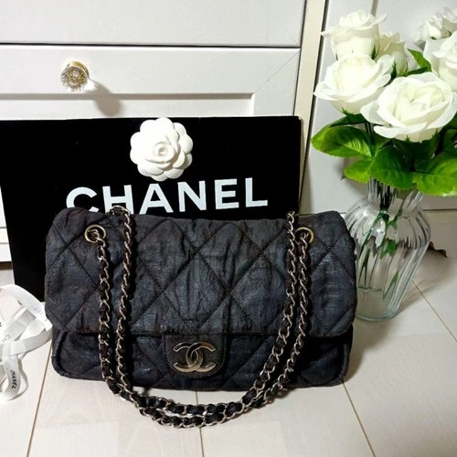 Black quilted Chanel bag with a chain strap in front of a Chanel box