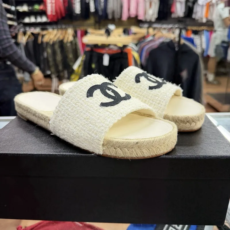 Cream Chanel espadrille slides with the CC logo on a Chanel box