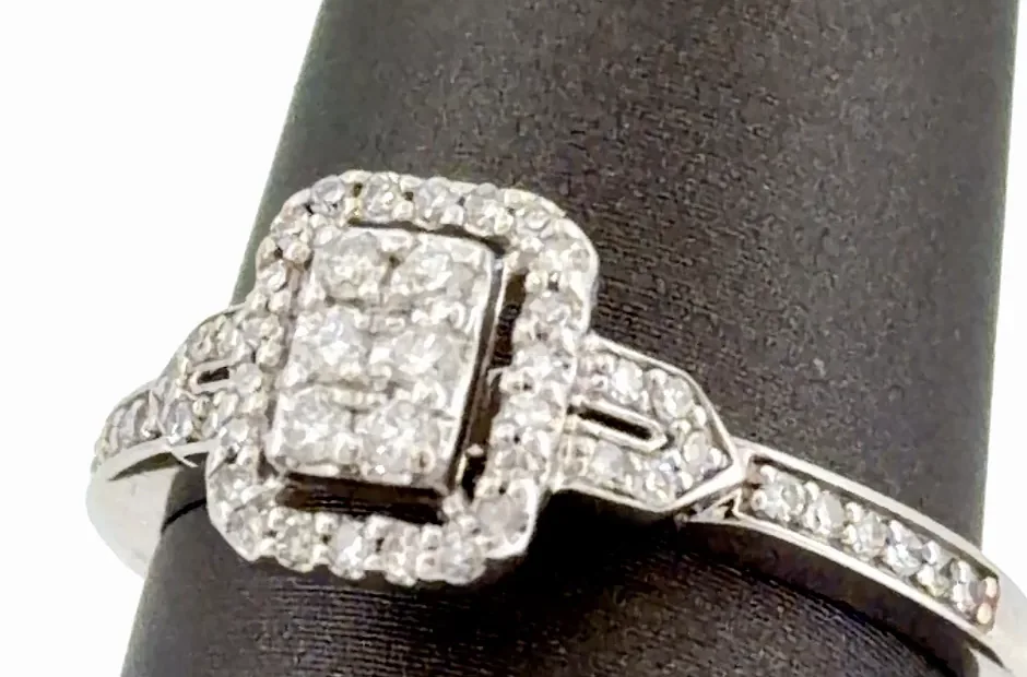 Close-up of a cluster diamond ring showing six small round diamonds in an illusion-set center inside a rectangular halo