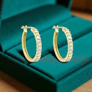 Yellow gold hoop earrings set with a row of baguette-cut stones in a green velvet box