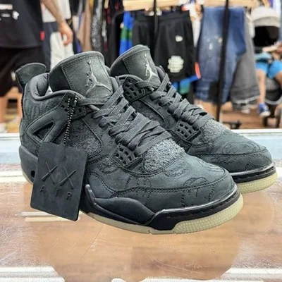 Black suede KAWS x Air Jordan 4 sneakers with the KAWS hangtag