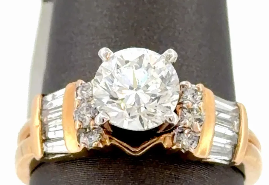 Close-up of a round center diamond in four white gold prongs with round side diamonds and channel-set tapered baguettes on a yellow gold ring