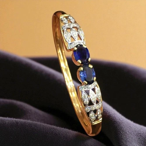 Yellow gold bangle with two oval blue sapphires and diamond-set openwork shoulders