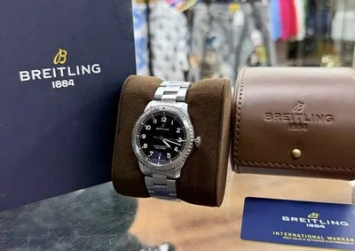 Breitling watch on a pillow with its Breitling box, travel pouch and warranty card